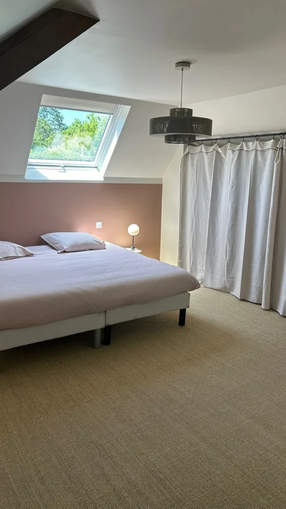 Chambre sous combles rénovée avec moquette et fenêtre de toit