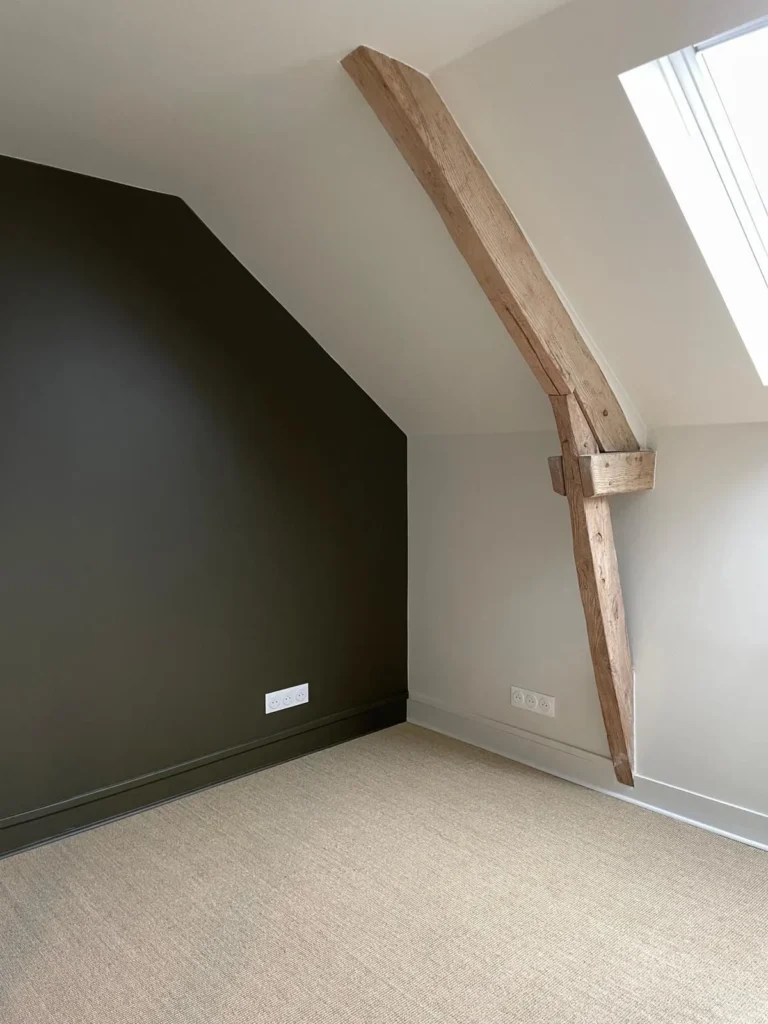 Chambre mansardée avec un mur peint en noir et poutre apparente